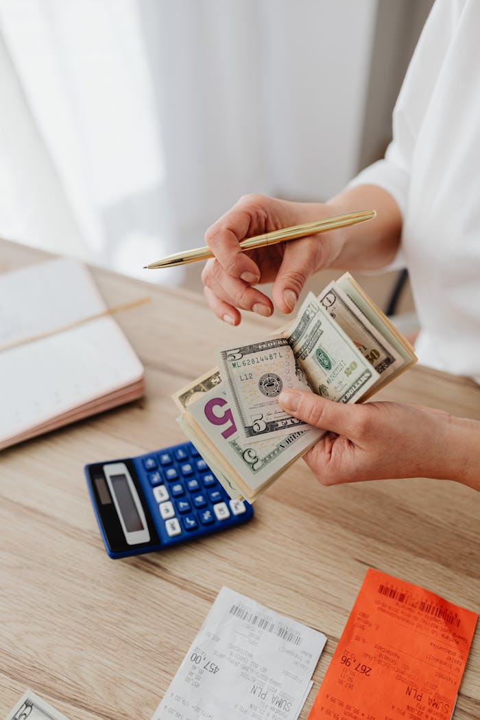 Woman counting money with calculator and receipts on a desk, planning budget.